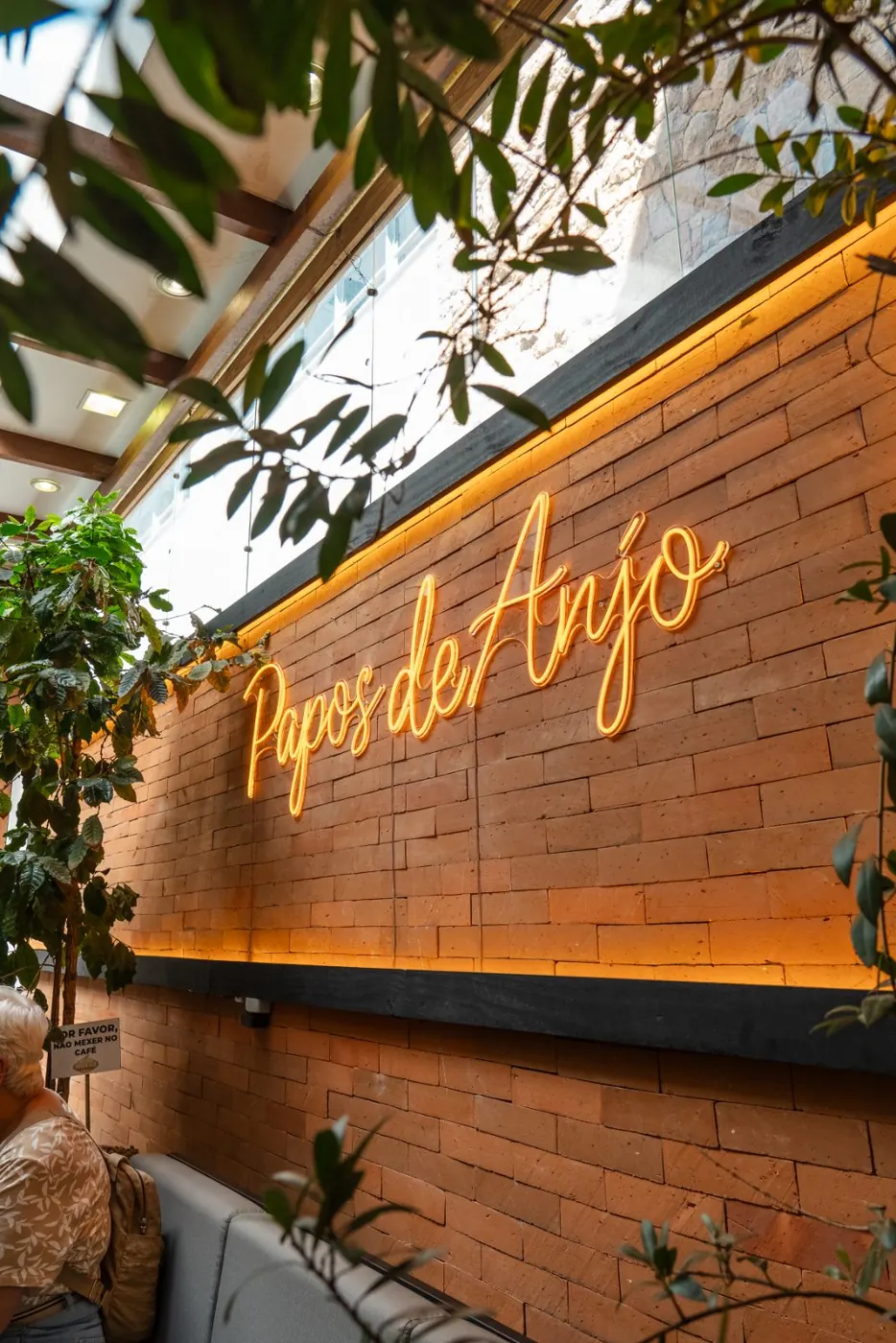 Letreiro Papos de Anjo em neon na parede de tijolos